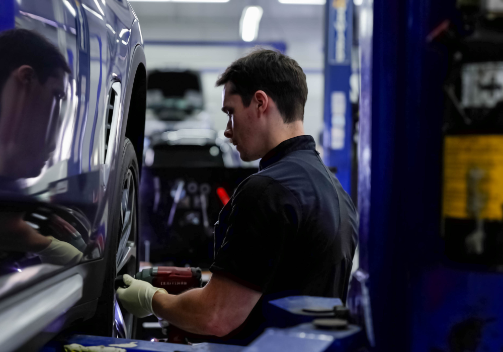 Service tech working on the front wheel of a car