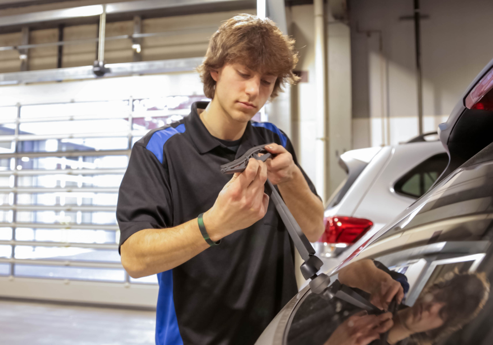 Kia service tech replacing the back windshield wiper of a car